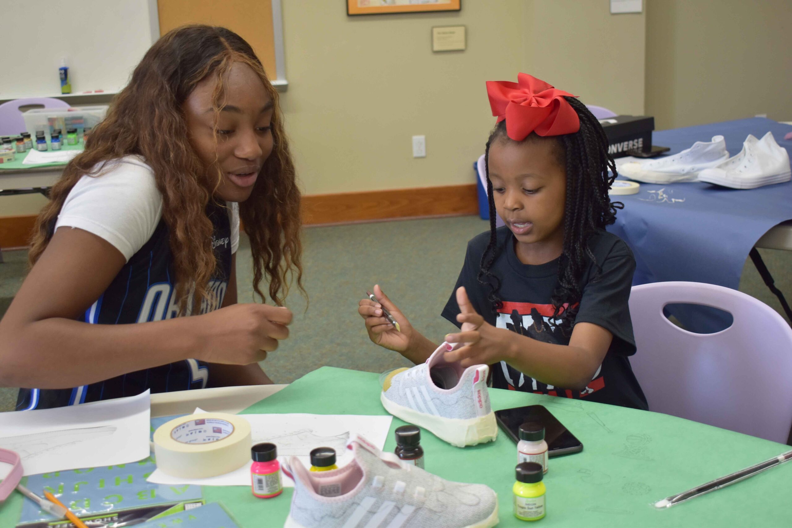Artist, Gabby Anderson provides instruction to Camden Smith